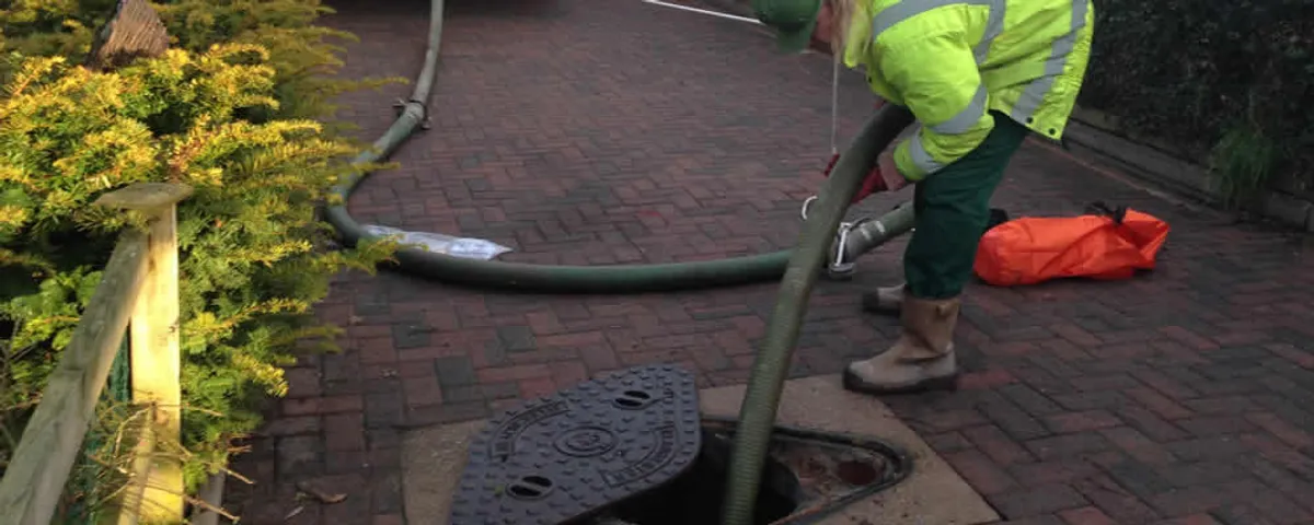 Septic tank cleaning technician servicing a septic tank with a vacuum hose in Fort Lauderdale, FL